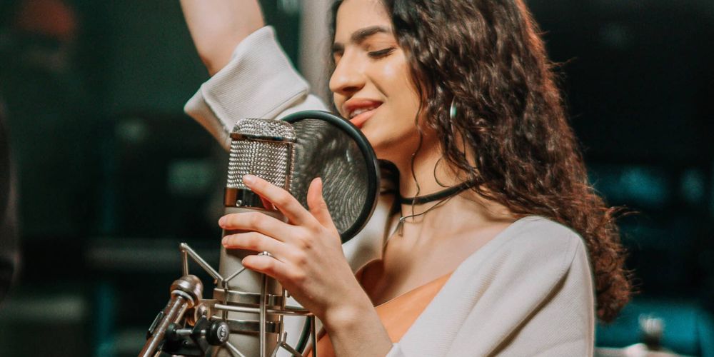 Cantante grabando una sesión vocal con micrófono profesional en estudio de grabación