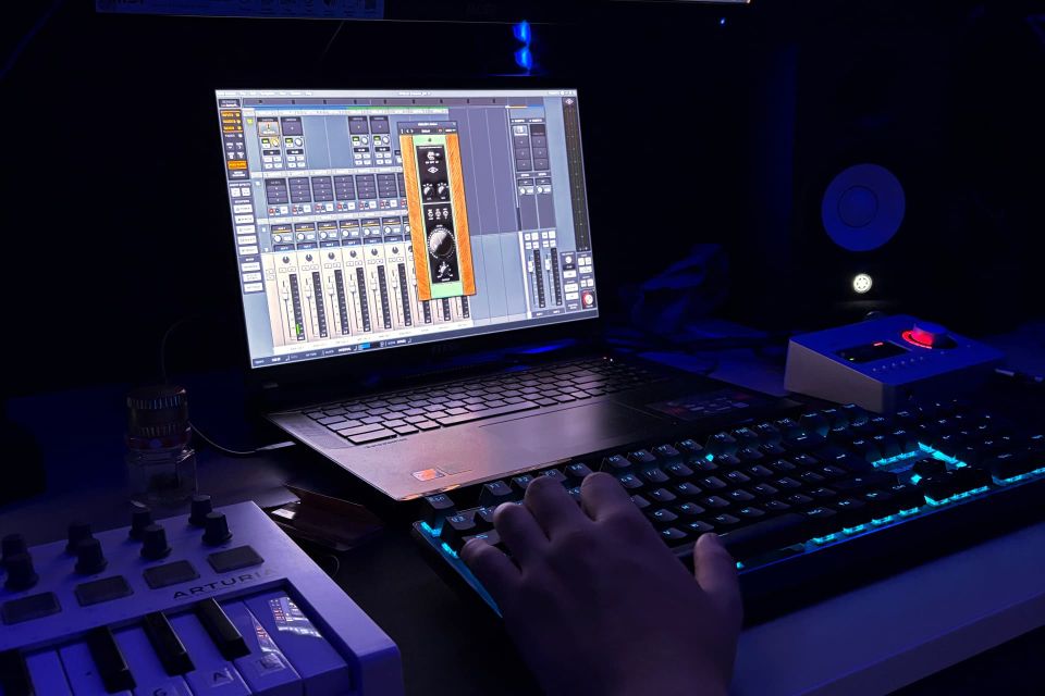 Productor trabajando en Ableton Live con monitor dual, controlador MIDI Arturia, teclado mecánico RGB y software de síntesis.