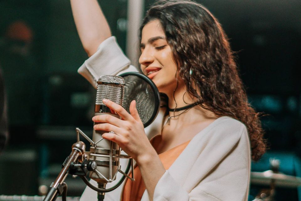 Cantante grabando una sesión vocal con micrófono profesional en estudio de grabación