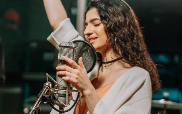 Cantante grabando una sesión vocal con micrófono profesional en estudio de grabación